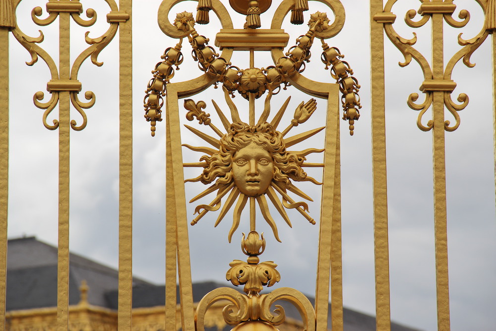 Detail of one of the gates of the palace of Versailles depicting the Sun King